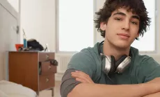 teenage boy in his bedroom looks at camera