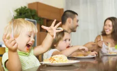 family around the dinner table eating spaghetti