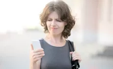 woman looks at phone with unhappy expression