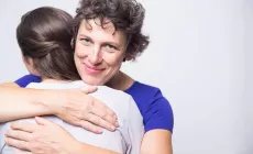 mother embracing teenage girl while looking at camera