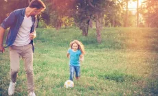 dad playing backyard soccer with daughter