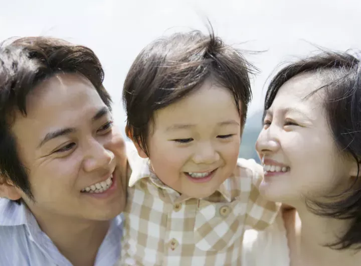 boy hugging parents around necks